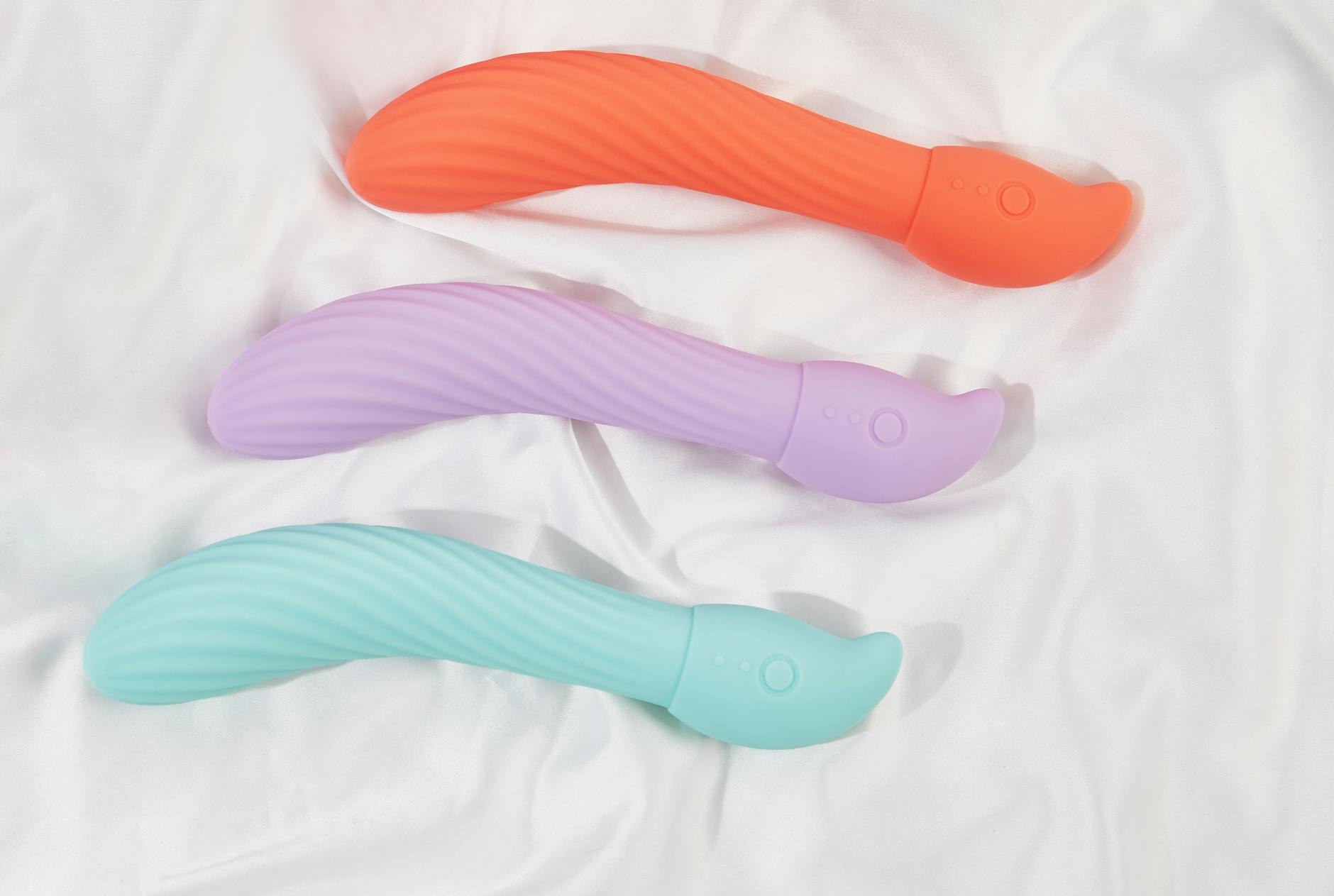 Three colorful vibrators arranged on white fabric, highlighting their smooth texture and design options