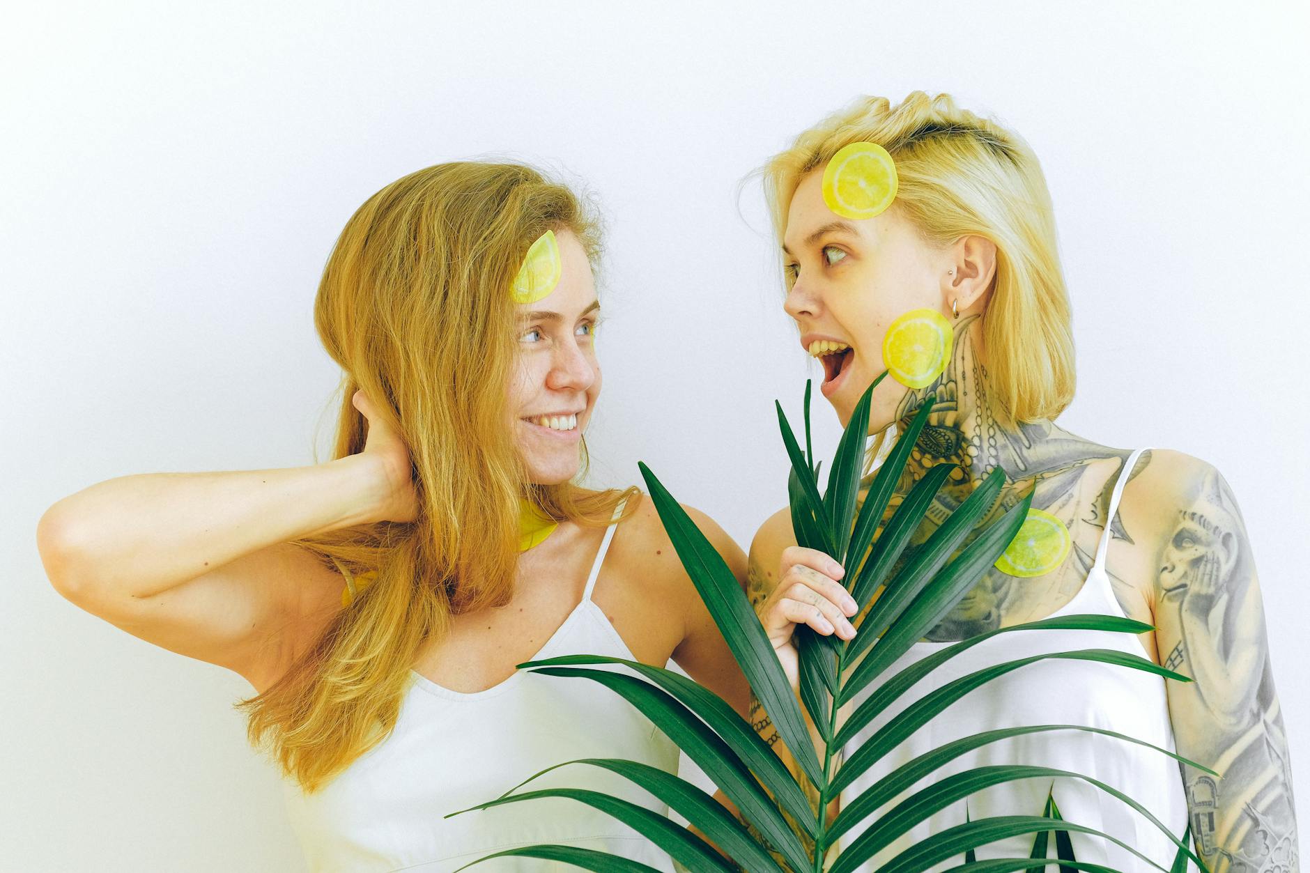 Two women smiling and enjoying time together with citrus slices, expressing joy and connection