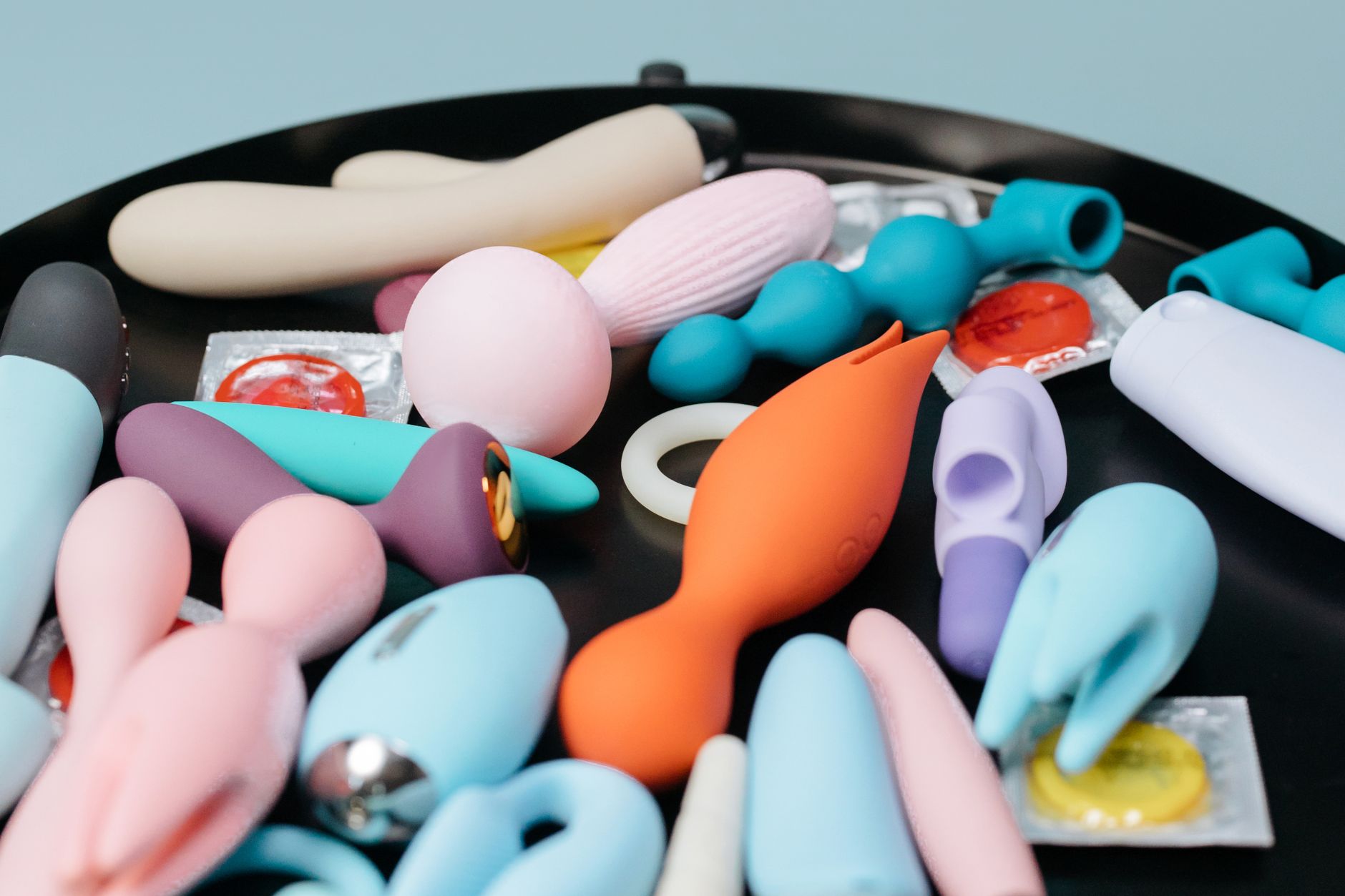 A collection of colorful sex toys on a black tray, showing diverse options and designs.
