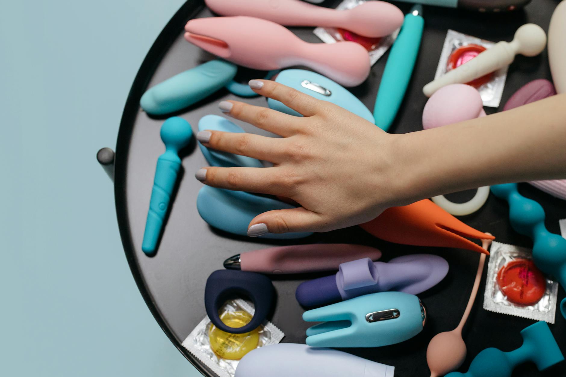 A close-up view of various colorful clitoral vibrators and sex toys arranged together, representing different options for safe pleasure