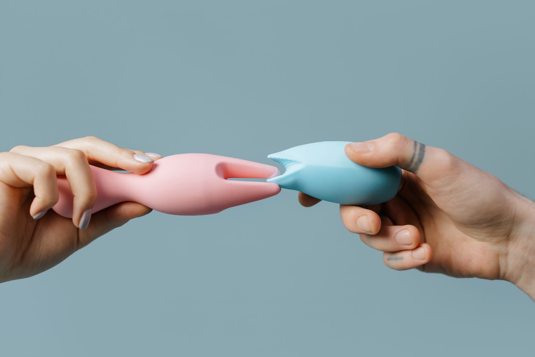 Intimate close-up of hands holding a sleek blue vibrator against a purple background