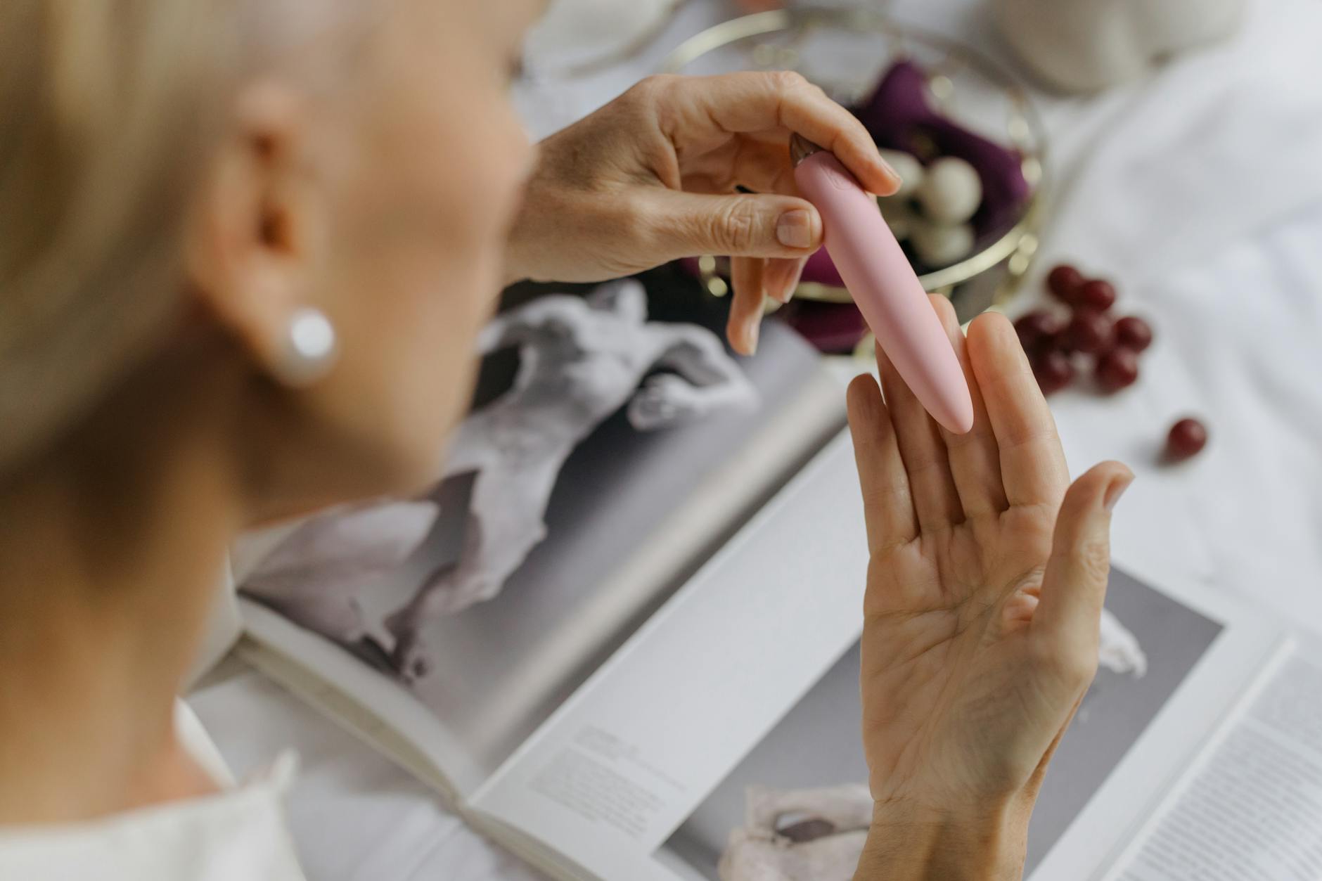 Woman holding a pink vibrator with intimate home setting, representing reconnecting with solo pleasure